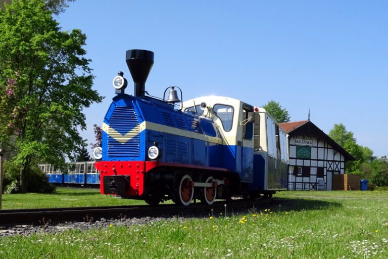 niebieska lokomotywka z wagonami wyjezdza ze stacji maltanka