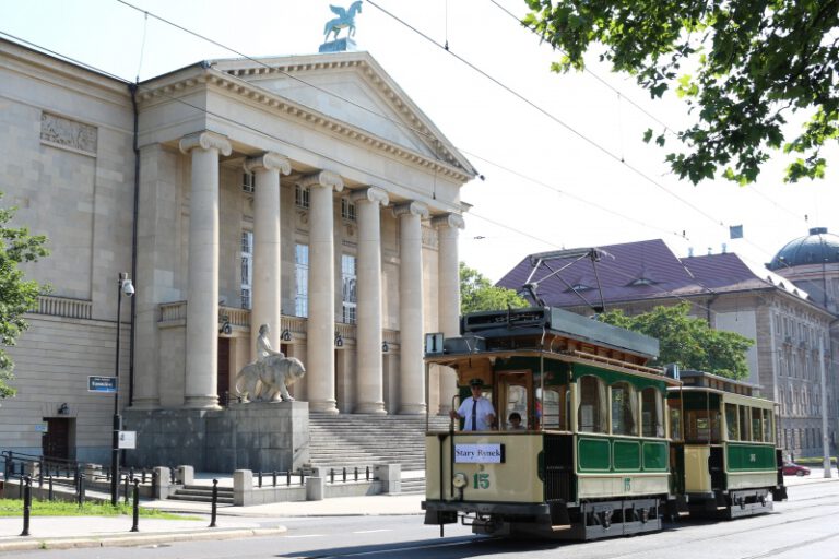 Stary, kremowo-ciemnozielony tramwaj przed gmachem opery w Poznaniu