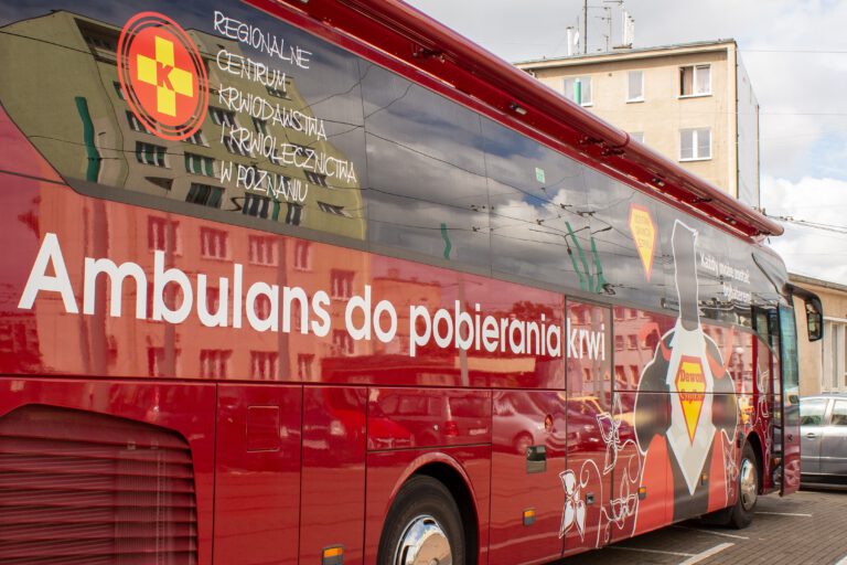 Na zdjęciu widnieje czerwony autobus z napisem Ambulans do pobierania krwi