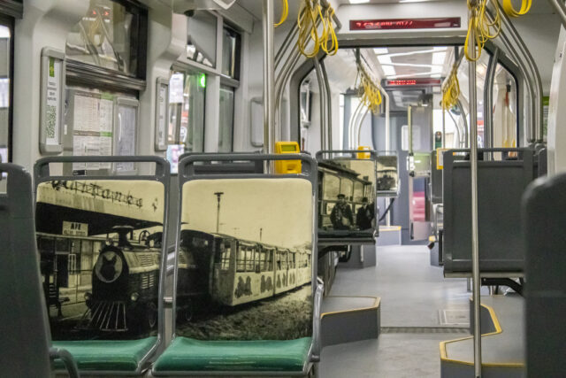 Czarno-białe zdjęcie kolejki Maltanka na oparciach dwóch siedzeń w tramwaju
