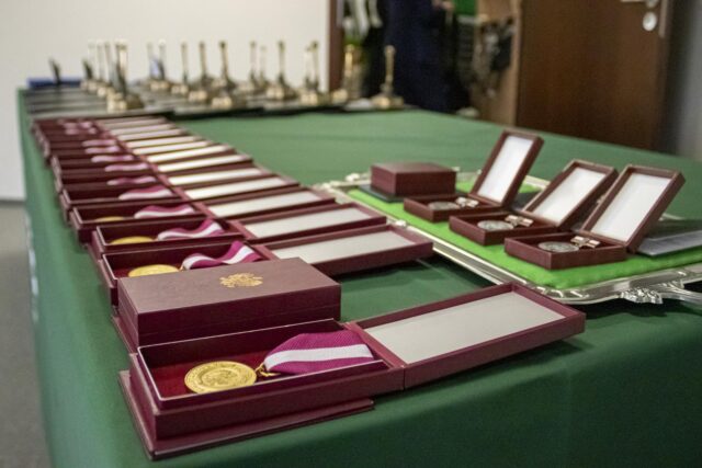 Medale w pudełkach, ułożone na stole, na zielonym obrusie