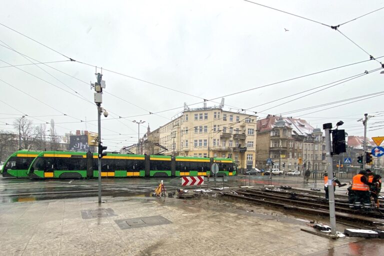 Prace na torowisku, w tle przejeżdżające zielono-żółte tramwaje MPK Poznań