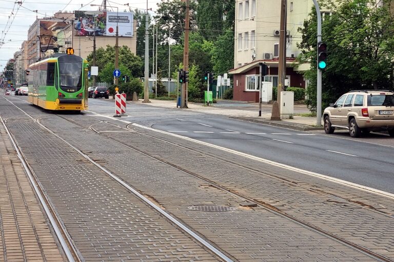 Tramwaj na torowisku, widoczne uszkodzone betonowe kostki przy torach