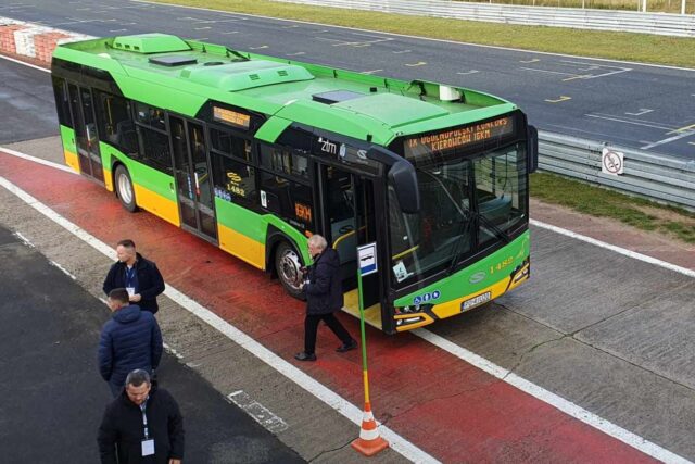 Autobus przy tymczasowym przystanku. Przy nim kilka osób z komisji konkursowej