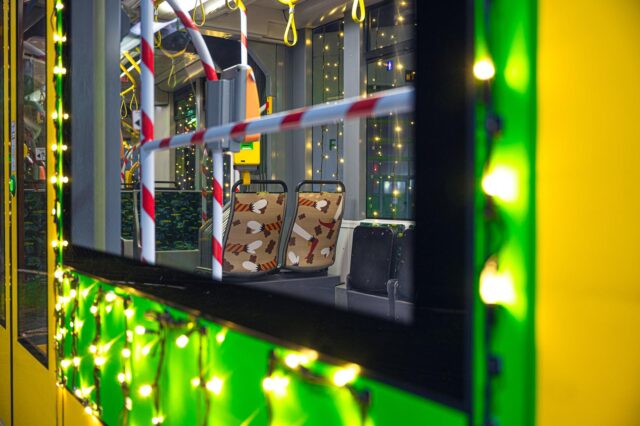 Ozdobione siedzenia pokazane zza okna rozświetlonego lampkami tramwaju