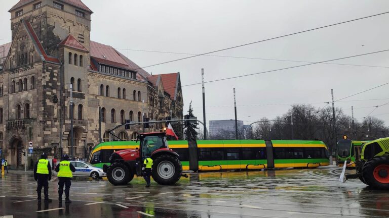 Patrol policji na skrzyżowaniu w Poznaniu. Widoczne traktory i tramwaj