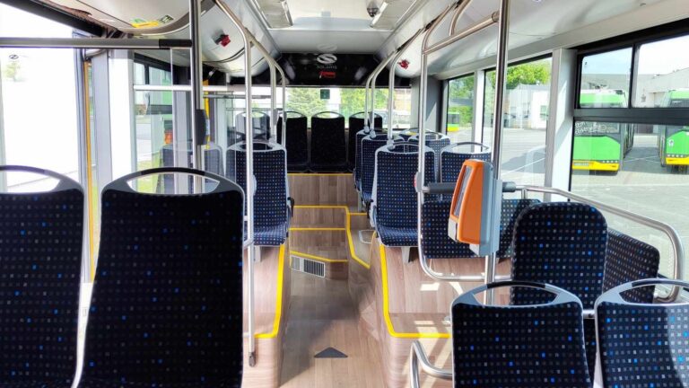 Wnętrze autobusu - przypominająca drewnianą podłoga z granatowe siedzenia