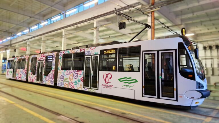 Oklejony tramwaj z piktogramami oraz logotypami MPK Poznań i Posnanii na terenie hali postojowej