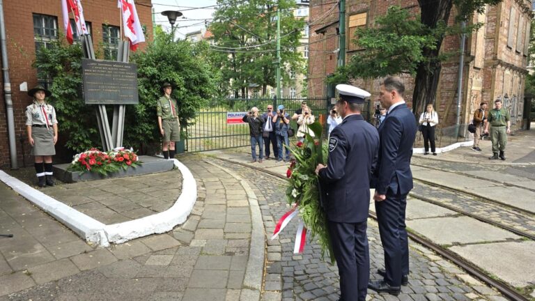 Przedstawiciele MPK Poznań z wieńcem przed pomnikiem przy bramie dawnej zajezdni Gajowa