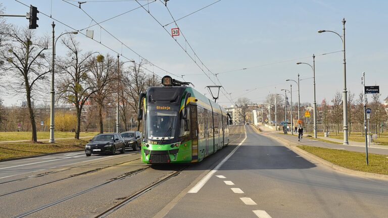 Tramwaj na torowisku. Widoczne uszkodzenia asfaltu przy szynach