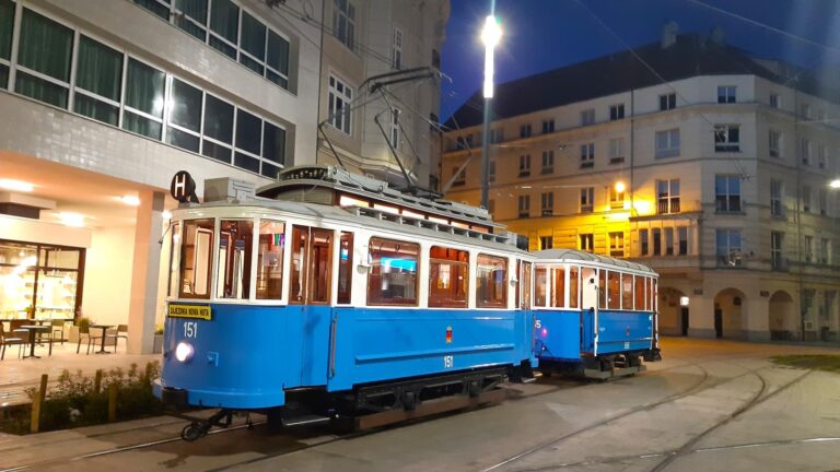 Historyczny niebieski tramwaj. W tle oświetlone nocą kamienice