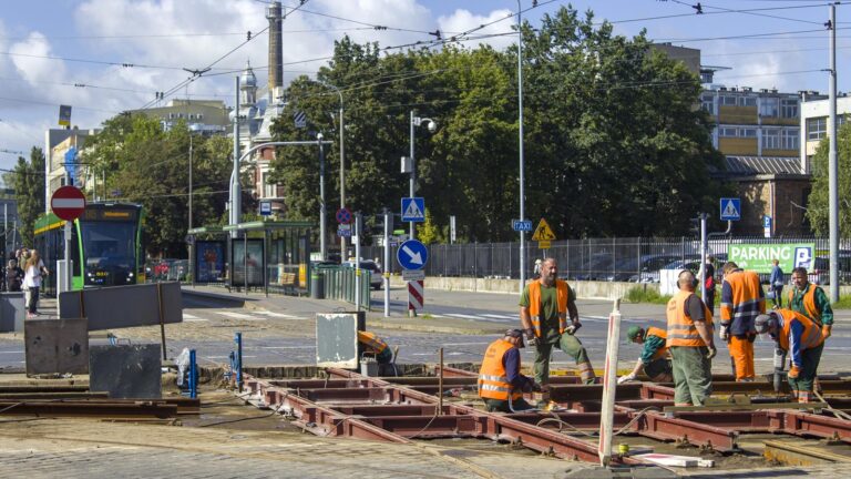 Robotnicy układają nowe torowisko. W tle tramwaj