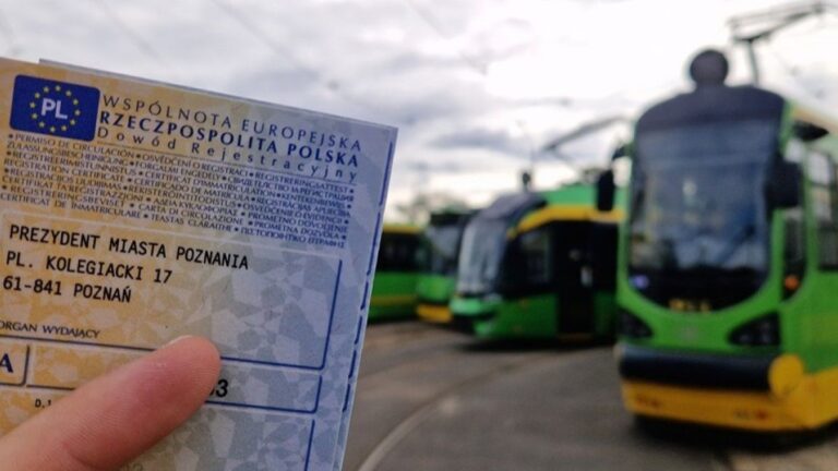Trzymany w ręku dowód rejestracyjny samochodu, w tle tramwaje