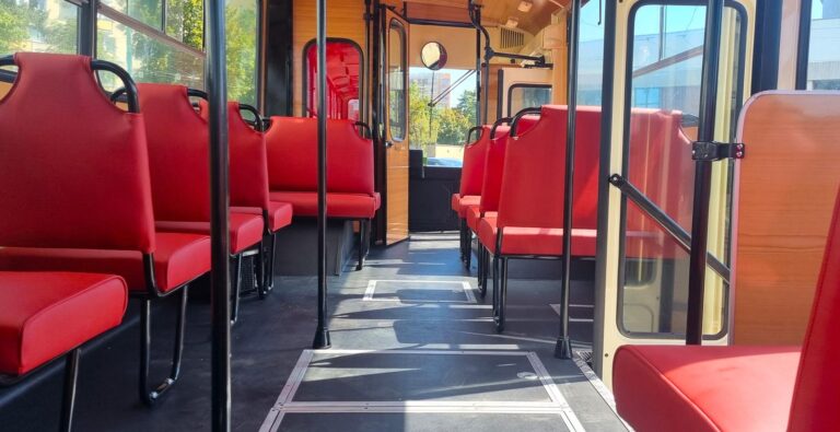 Wnętrze historycznego autobusu, widoczne czerwone siedzenia