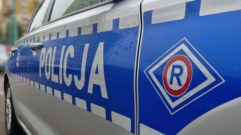 Napis policja i znak służby ruchu drogowego na boku radiowozu