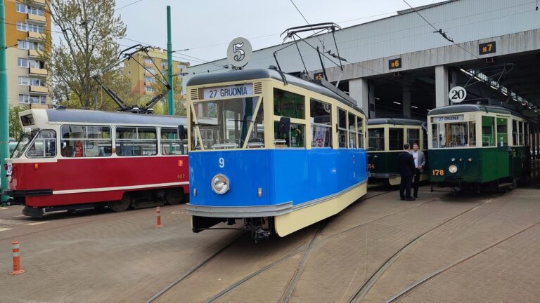 Trzy tramwaje czerwony, niebieski i zielony przed halą