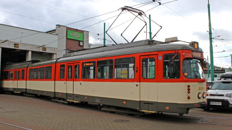 Kremowo-pomarańczowy tramwaj z widocznym numerem taborowym 907