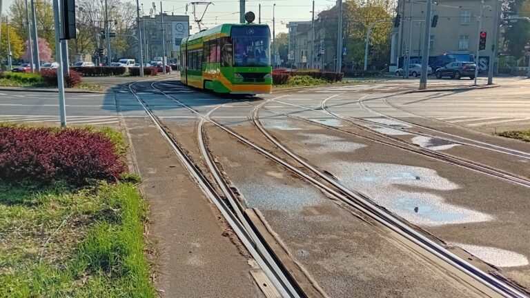 Tramwaj na rondzie. Widoczna uszkodzona nawierzchnia przy torowisku