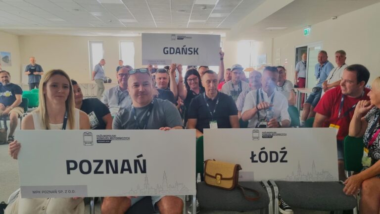 Zawodnicy podczas narady. Widoczne tablice z nazwami miast Poznań, Gdańsk, Łódź