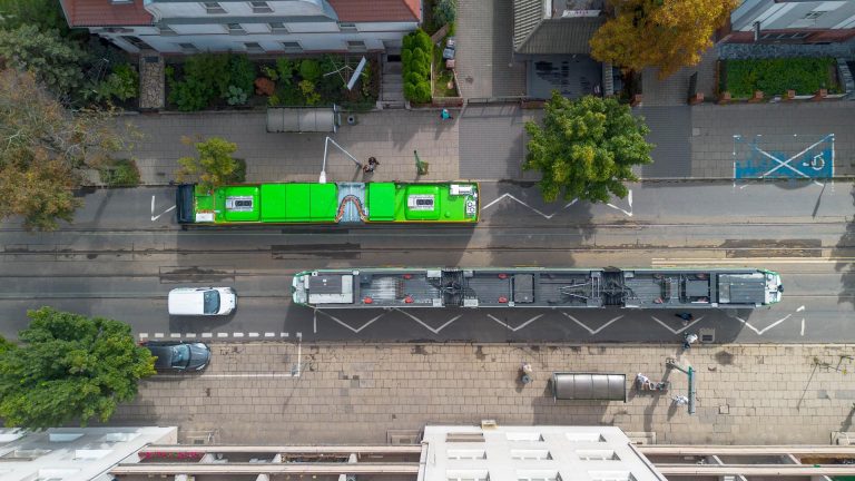 Zdjęcie z góry. Widoczne dachy tramwaju i autobusu oraz zniszczona nawierzchnia i torowisko