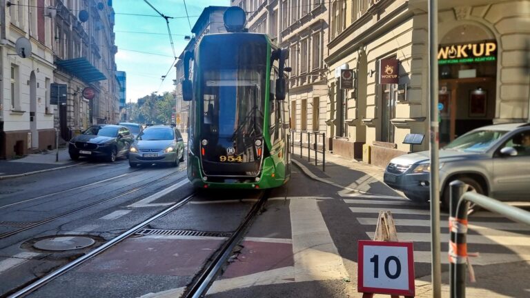Znak ograniczenia prędkości do 10 km na godzinę, a za nim jadący tramwaj